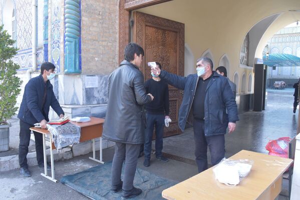 Людей встречают работники Комитета по делам религии, которые проверяют всех на наличие повышенной температуры, предлагают защитные маски тем, у кого их нет, и предупреждают о том, как нужно вести себя во время служения - Sputnik Таджикистан