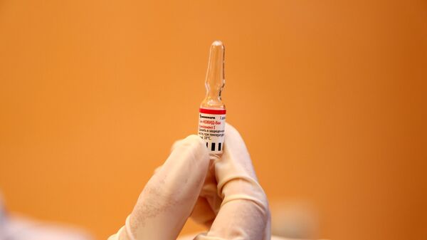 Медицинский работник держит в руке вакцину от COVID-19 Спутник-V  - Sputnik Таджикистан