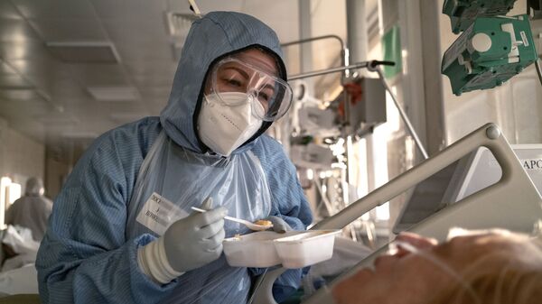 Медсестра кормит пациента в отделении реанимации и интенсивной терапии в больнице в Москве - Sputnik Тоҷикистон
