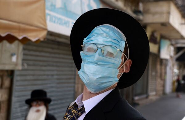 Мужчина в защитных масках на лице во время празднования Пурима в Иерусалиме. - Sputnik Тоҷикистон