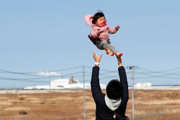 Потерявший родных во время землетрясения 2011 года отец с ребенком в префектуре Фукусима  - Sputnik Таджикистан