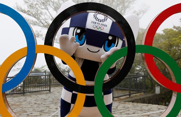 Талисман Олимпийских игр в Токио Мирайтова позирует с изображением олимпийского символа после церемонии открытия символа - Sputnik Таджикистан