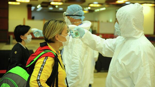 Медицинские работники в аэропорту Манас проверяют температуру прибывших. Архивное фото - Sputnik Тоҷикистон
