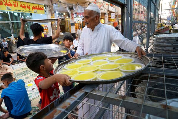 Иракские мусульмане несут тарелки для бесплатного коллективного ифтара в Наджафе, Ирак - Sputnik Таджикистан