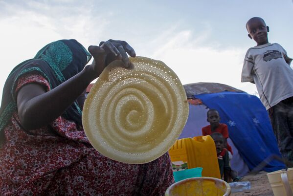 Сомалийская женщина готовит блины для своей семьи в лагере для мигрантов в Могадишо, Сомали - Sputnik Таджикистан