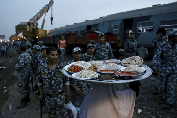 Женщина приносит еду для сил безопасности на место сошедшего с рельсов пассажирского поезда в Египте - Sputnik Таджикистан