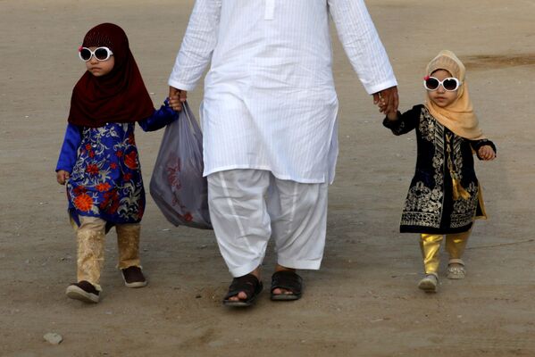 Отец с детьми возвращается после праздничной молитвы в Пакистане - Sputnik Таджикистан