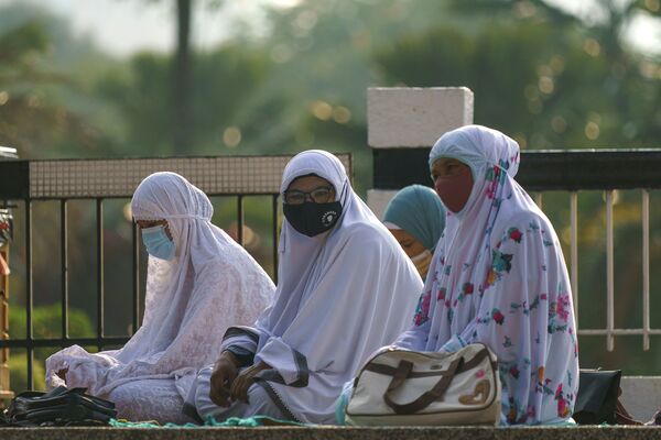 Мусульманские женщины в защитных масках ждут, чтобы помолиться возле Национальной мечети в Малайзии - Sputnik Таджикистан