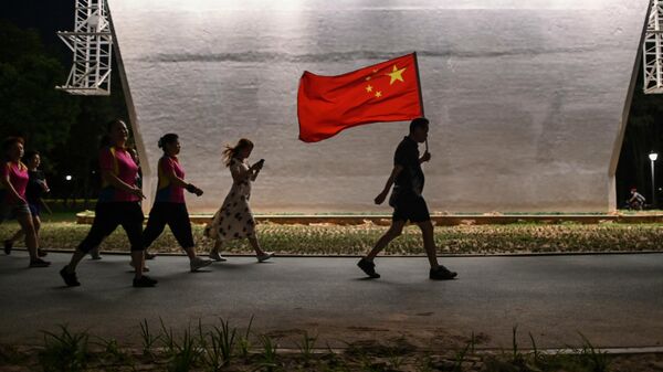 Мужчина с флагом Китая идет по парку в Ухане - Sputnik Таджикистан