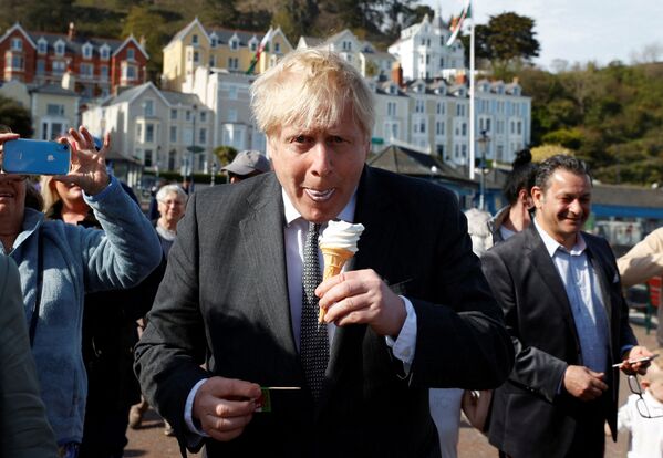 Премьер-министр Великобритании Борис Джонсон ест мороженое во время кампании в Лландидно, северный Уэльс, 2021 год - Sputnik Таджикистан