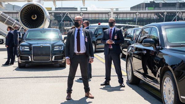 Сотрудники службы безопасности охраняют лимузины президента России рядом с самолетом президента России Владимира Путина - Sputnik Таджикистан