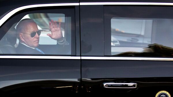 Президент США Джо Байден машет рукой в машине - Sputnik Тоҷикистон