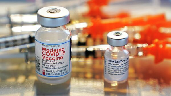 Флаконы с вакцинами Moderna и Pfizer COVID-19 выставлены на подносе в клинике - Sputnik Таджикистан