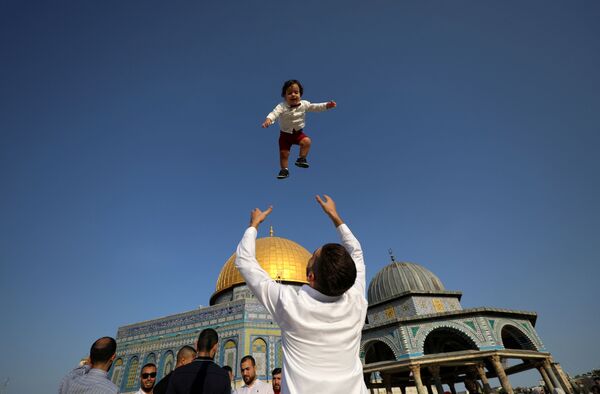 Родитель в Палестине подкидывает ребенка во время празднования Курбан-байрама. - Sputnik Таджикистан