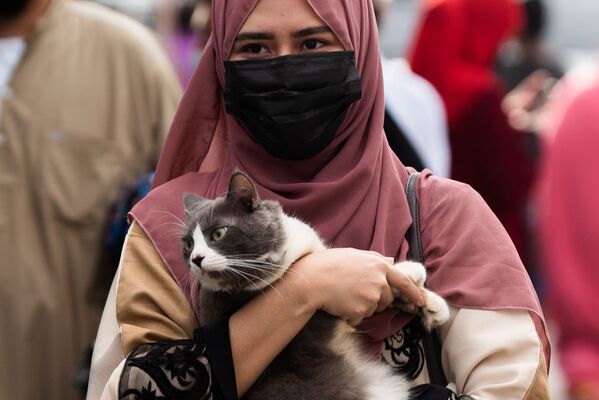 Филиппинская девушка в защитной маске несет кошку после утренней молитвы в Курбан-байрам возле Голубой мечети в городе Тагиг. - Sputnik Таджикистан