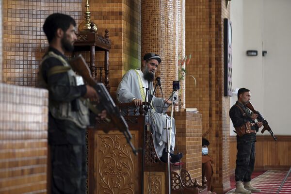 Священнослужитель в сопровождении вооруженных сил безопасности общается с людьми в мечети во время праздничной молитвы в Кабуле, Афганистан. - Sputnik Таджикистан