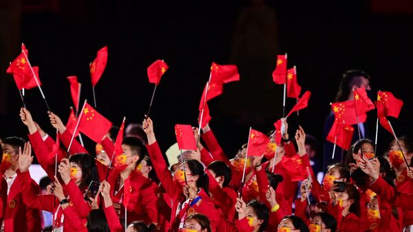 Члены китайской делегации машут флагами, входя на Олимпийский стадион во время церемонии открытия в Токио - Sputnik Таджикистан