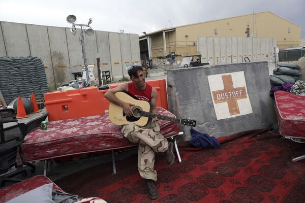 Афганский солдат играет на гитаре на покинутой американцами авиабазе Баграм - Sputnik Таджикистан
