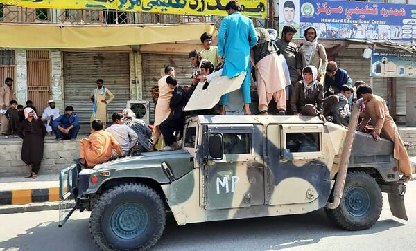 Талибы и местные жители садятся в автомобиль Humvee Афганской национальной армии (АНА) на обочине дороги в провинции Лагман - Sputnik Таджикистан