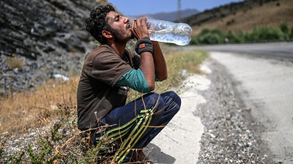 Афганский мигрант пьет воду в Татване - Sputnik Тоҷикистон