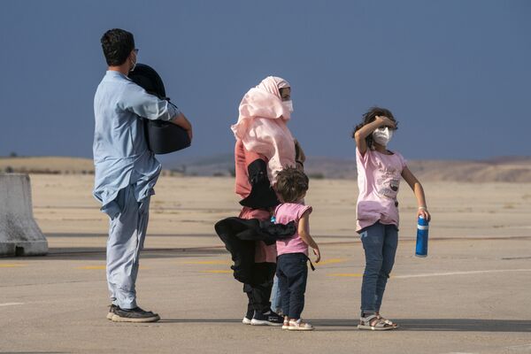 Афганская семья ждет на взлетно-посадочной полосе после высадки из самолета на военной базе Торрехон в Мадриде. - Sputnik Таджикистан