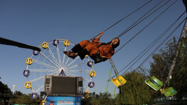 Афганская женщина катается на карусели в парке развлечений в Кабуле - Sputnik Таджикистан
