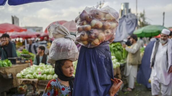 Женщина в парандже несет на голове мешок с луком на рынке в Кабуле - Sputnik Тоҷикистон
