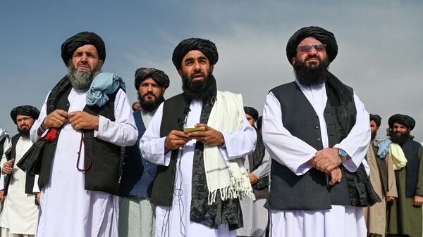 Представитель Талибана Забихулла Муджахид (в центре) обращается к СМИ в аэропорту Кабула - Sputnik Тоҷикистон