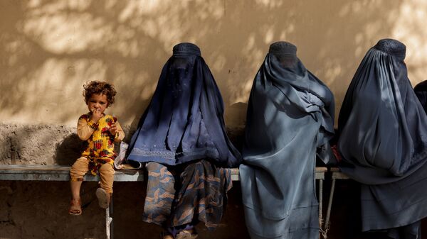 Девочка рядом с женщинами в бурке у больницы в Кабуле  - Sputnik Таджикистан