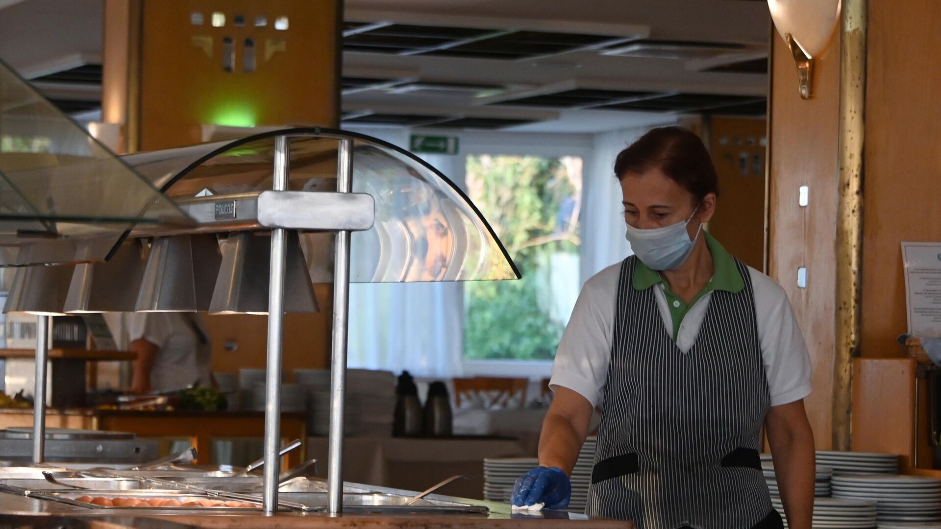 Сотрудница ресторана в защитной маске и перчатках во время уборки - Sputnik Таджикистан, 1920, 07.02.2022