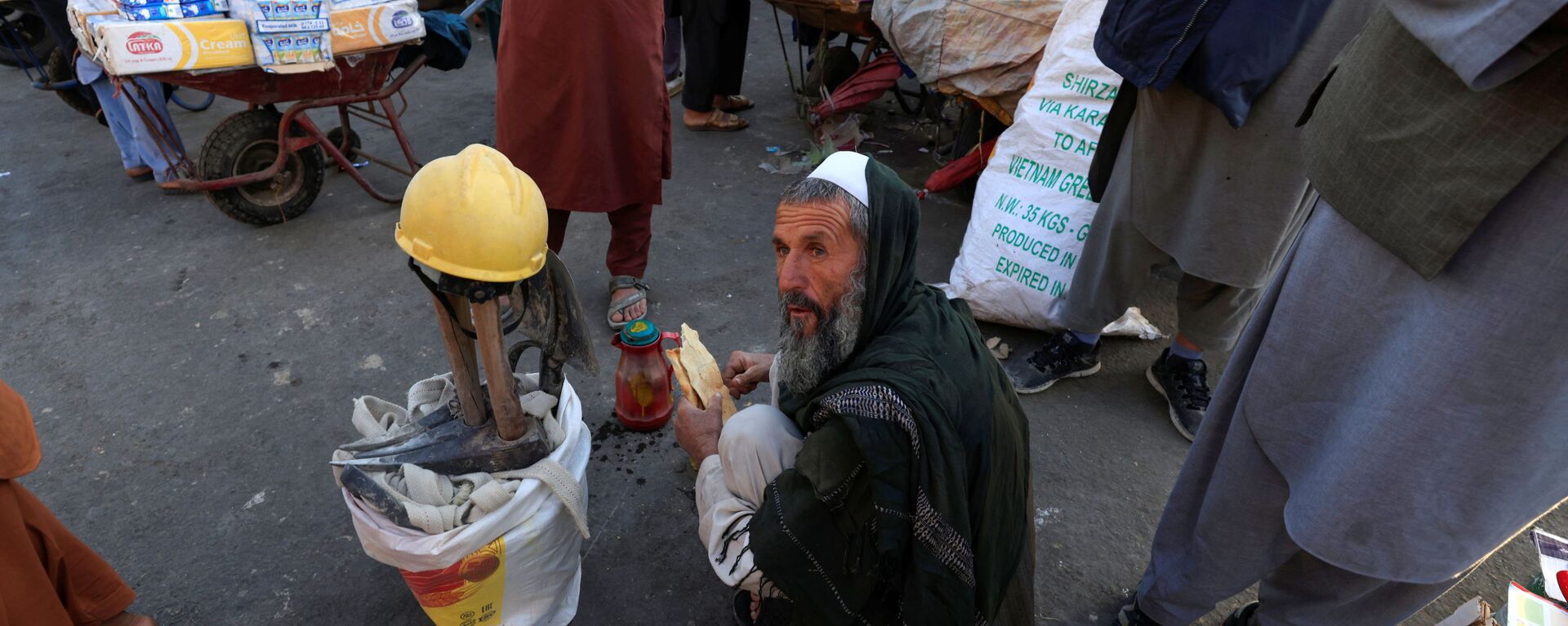 55-летний Гул Мохаммад завтракает, сидя рядом со своими инструментами в ожидании работы на рынке в Кабуле, Афганистан - Sputnik Тоҷикистон, 1920, 08.12.2021