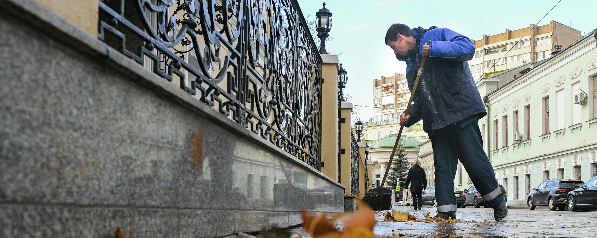 Сотрудник коммунальной службы подметает листья на улице в Москве. - Sputnik Тоҷикистон, 1920, 25.11.2021