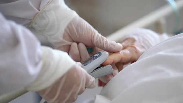 Медицинский работник измеряет уровень кислорода в крови пациенту - Sputnik Таджикистан