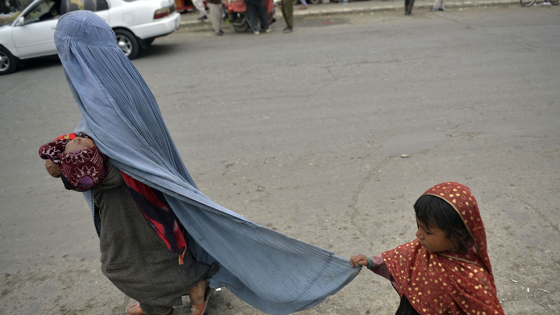 Женщина в бурке с ребенком на улице в Кабуле - Sputnik Тоҷикистон, 1920, 14.07.2022