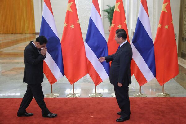 Премьер-министр Таиланда Прают Чан-О-Ча произносит традиционное тайское приветствие, в то время как председатель КНР Си Цзиньпин протягивает ему руку. - Sputnik Таджикистан
