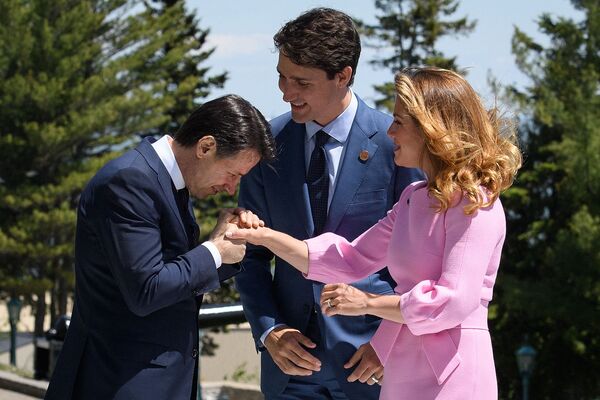 Премьер-министр Италии Джузеппе Конте делает вид, что целует руку Софи Грегуар, жены премьер-министра Канады Джастина Трюдо. - Sputnik Таджикистан