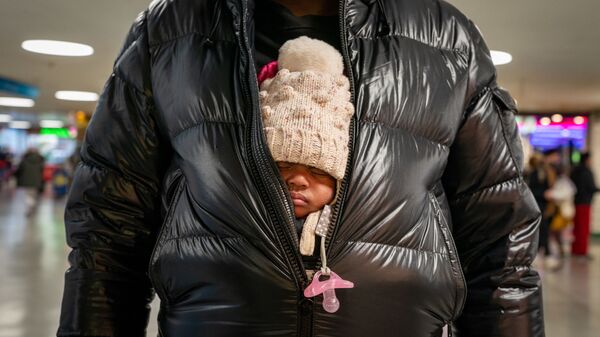 Мужчина держит маленького ребенка под курткой на Пенсильванском вокзале в Нью-Йорке - Sputnik Тоҷикистон