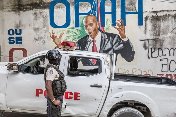 Полицейский стоит у граффити с президентом Гаити Жовенелем Мойзом, убитым наемником в Доминикане 7 июля. - Sputnik Таджикистан