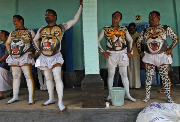 Индийские мужчины в костюмах с изображением тигра ждут, когда высохнет краска перед выступлением  на фестивале Пуликали. - Sputnik Таджикистан