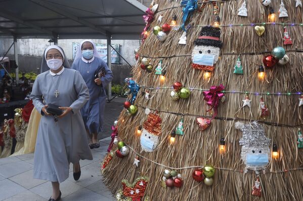 Монахини в масках проходят мимо рождественской елки с украшениями на тему коронавируса на Бали. - Sputnik Таджикистан