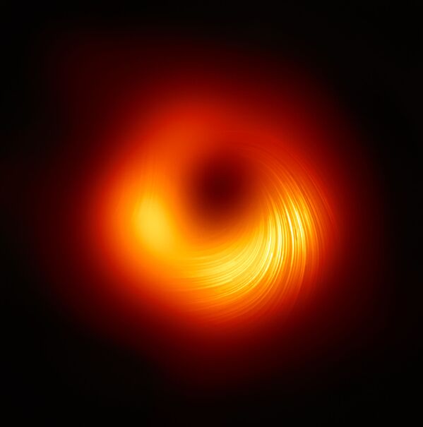Изображение телескопа Event Horizon, демонстрирующее поляризованный вид черной дыры M87. Линии обозначают ориентацию поляризации, которая связана с магнитным полем вокруг тени черной дыры. - Sputnik Таджикистан
