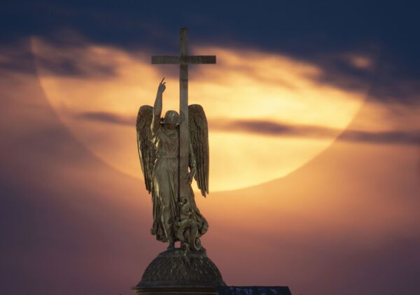 Полная луна поднимается к облакам над статуей ангела, установленной на вершине Александровской колонны на Дворцовой площади в Санкт-Петербурге. - Sputnik Таджикистан
