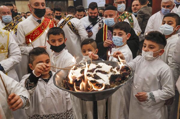 Юные алтарники зажигают свечи во время рождественской мессы в сирийской православной церкви Ум аль-Нур в Эрбиле, столице автономного курдского региона на севере Ирака. - Sputnik Таджикистан