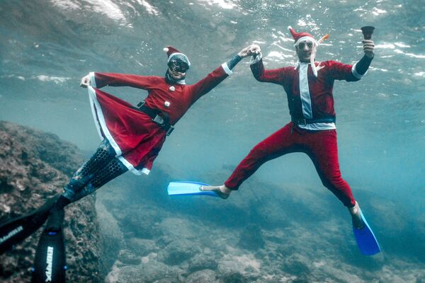 Фридайверы, одетые в костюмы Санта-Клауса, позируют под водой у побережья северного города Ливана Батрун. - Sputnik Таджикистан