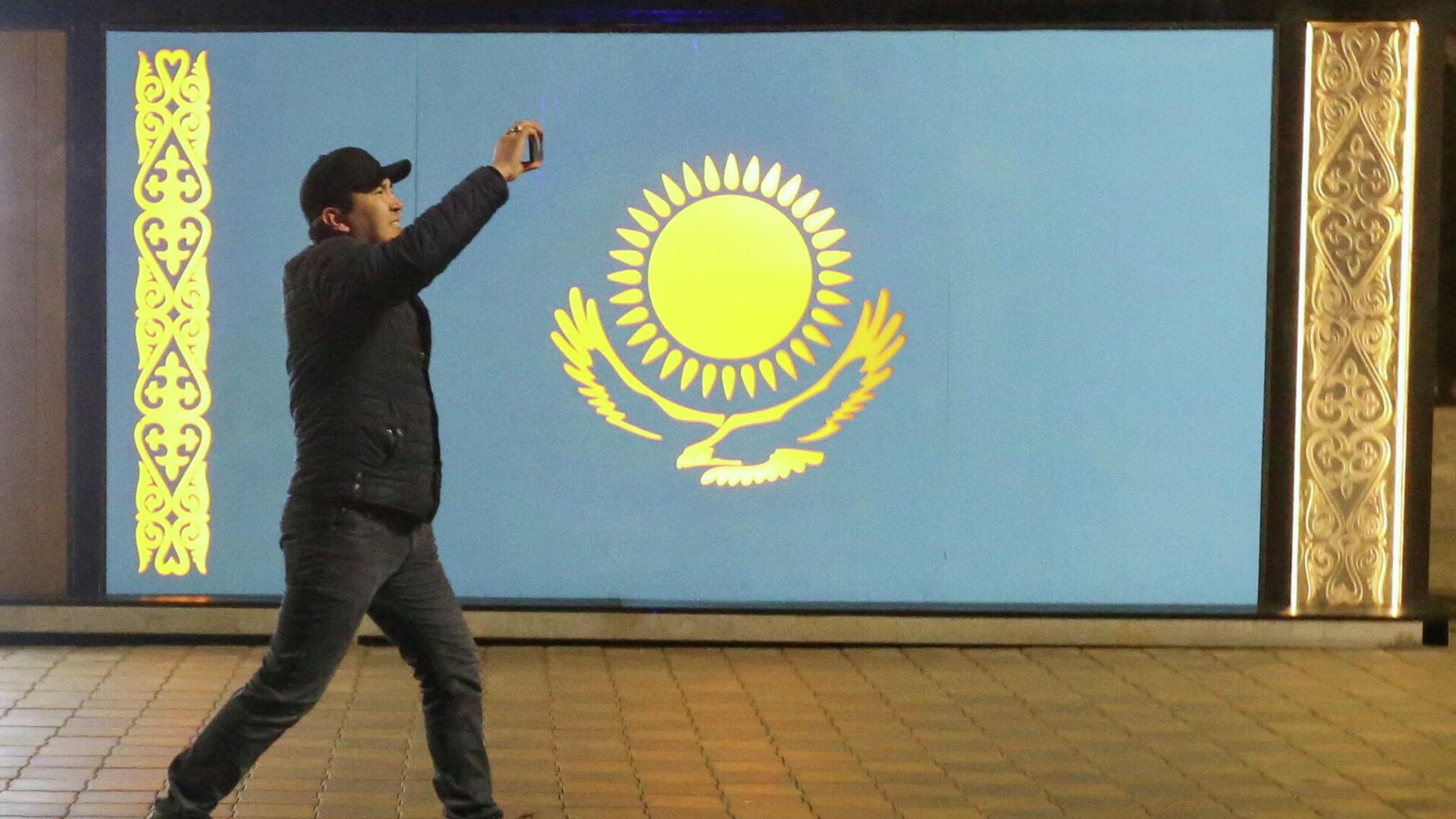 Протестующий идёт мимо государственного флага, Казахстан - Sputnik Тоҷикистон, 1920, 06.01.2022
