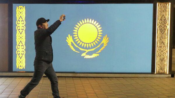 Протестующий идёт мимо государственного флага, Казахстан - Sputnik Тоҷикистон
