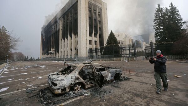 Сгоревший автомобиль перед зданием мэрии, которое было подожжено во время протестов в Алматы - Sputnik Тоҷикистон