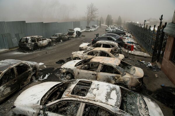 Сгоревшие автомобили на парковке в центре Алматы после череды массовых беспорядков, призывающих  внимание властей. - Sputnik Таджикистан