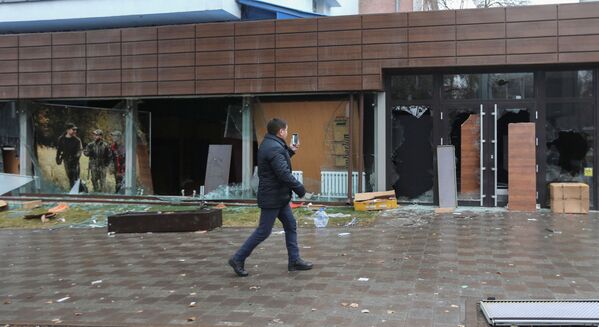 Казахстанец идет мимо разбитых окон магазина непродовольственных товаров после протестов в Алматы. - Sputnik Таджикистан