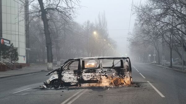 Автомобиль, сожженный во время протестов, вызванных повышением цен на топливо, на дороге в Алматы - Sputnik Таджикистан